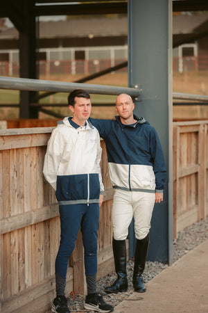 Two men in matching tracksuits standing next to a wooden fence.