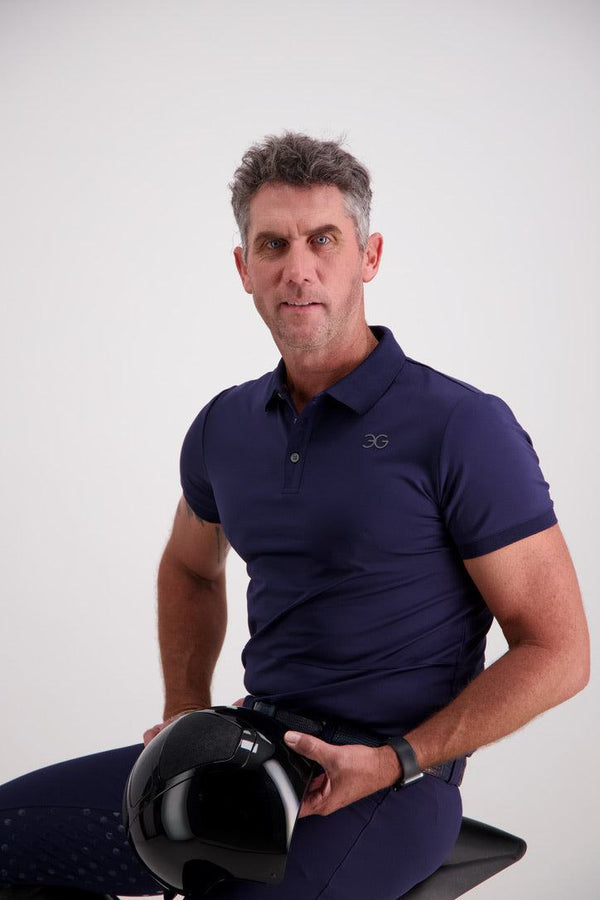 Man wearing a Gallant Equestrian Mens Equestrian Polo Shirt in navy, seated with a helmet.