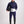 Man wearing Gallant Equestrian Mens Equestrian Rain Jacket in navy and bone, holding a helmet.