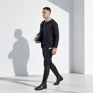 Mens Equestrian Hoodie in black, worn with riding breeches; lightweight fabric, hood, and asymmetrical front zip.